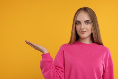 Photo of Special promotion. Young woman showing something on orange background, space for text