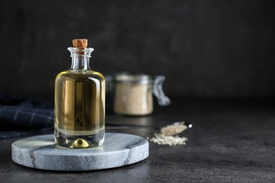 Sesame oil in glass bottle on dark grey table. Space for text