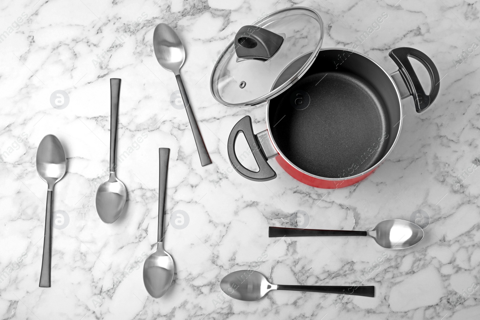 Photo of New spoons and empty pot on marble table, flat lay