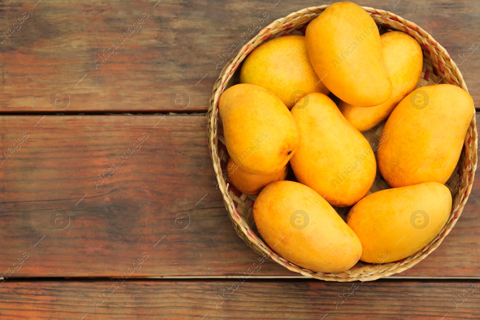 Photo of Delicious ripe juicy mangos on wooden table, top view. Space for text