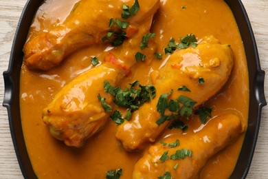 Tasty chicken curry with parsley on wooden table, top view