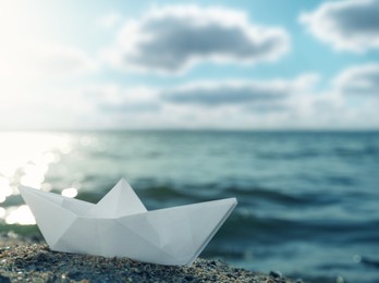 Image of White paper boat near river on sunny day 