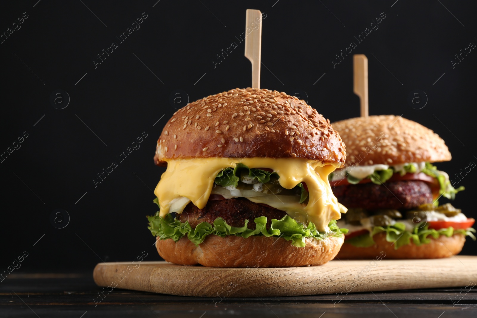 Photo of Vegetarian burgers with delicious patties on black wooden table, closeup