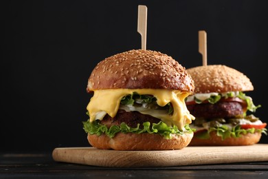 Photo of Vegetarian burgers with delicious patties on black wooden table, closeup