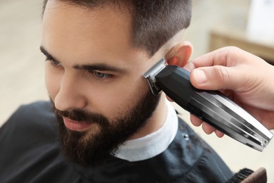 Professional hairdresser working with client in barbershop, closeup