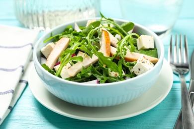 Photo of Delicious salad with chicken, arugula and feta cheese on light blue wooden table, closeup