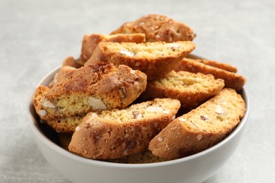 Traditional Italian almond biscuits (Cantucci) in bowl on light table, closeup