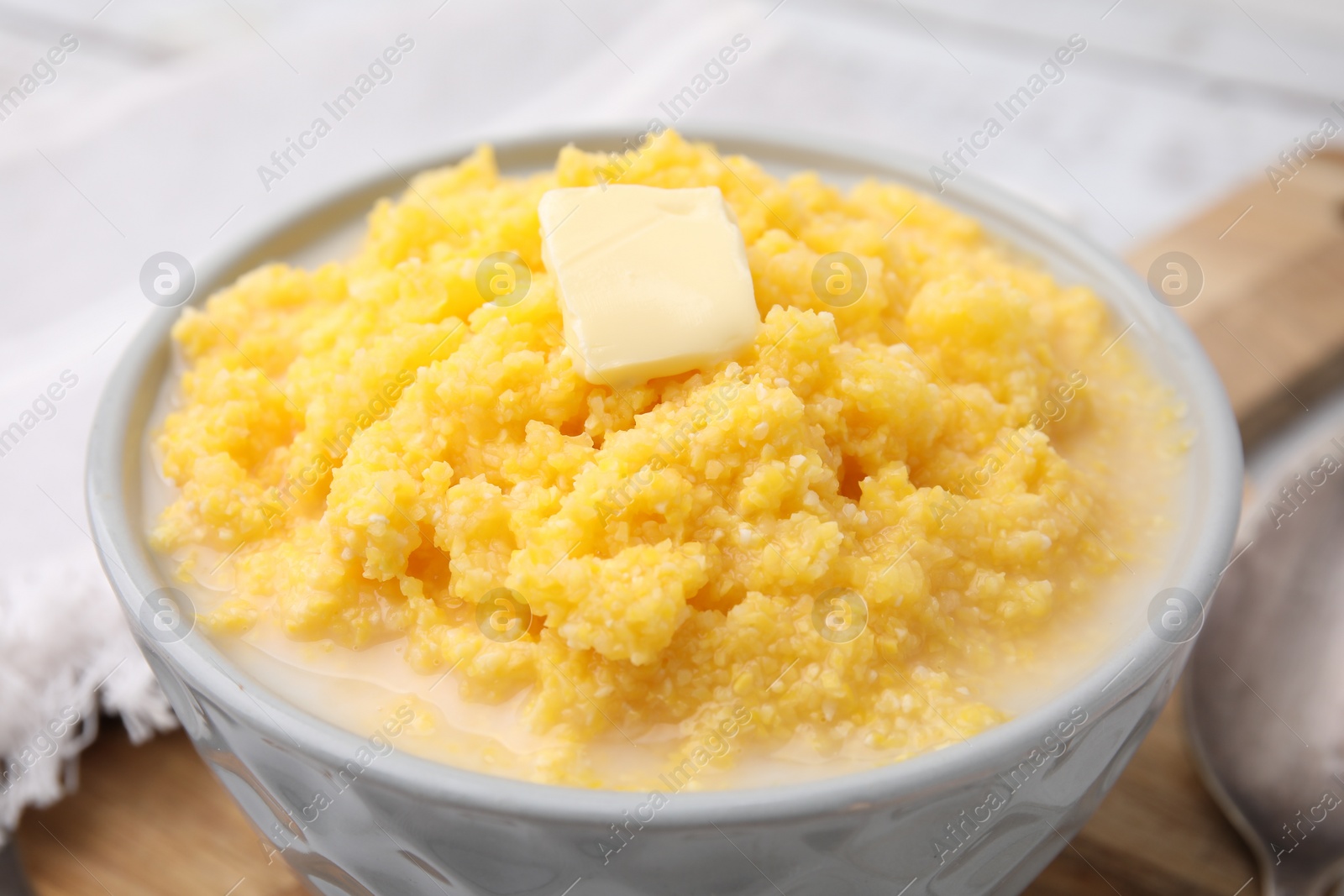 Photo of Tasty cornmeal with butter in bowl on table, closeup