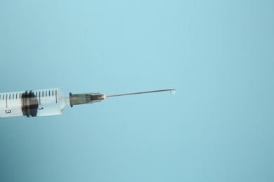 Photo of Medical syringe on light blue background, closeup. Space for text