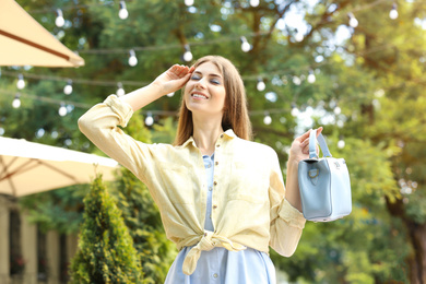 Photo of Beautiful young woman with elegant bag outdoors on summer day