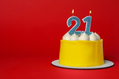 Photo of 21st birthday. Delicious cake with number shaped candles for coming of age party on red background, space for text