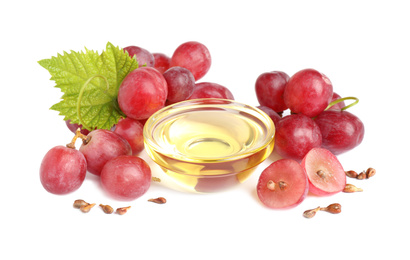 Organic red grapes, seeds and bowl of natural essential oil on white background