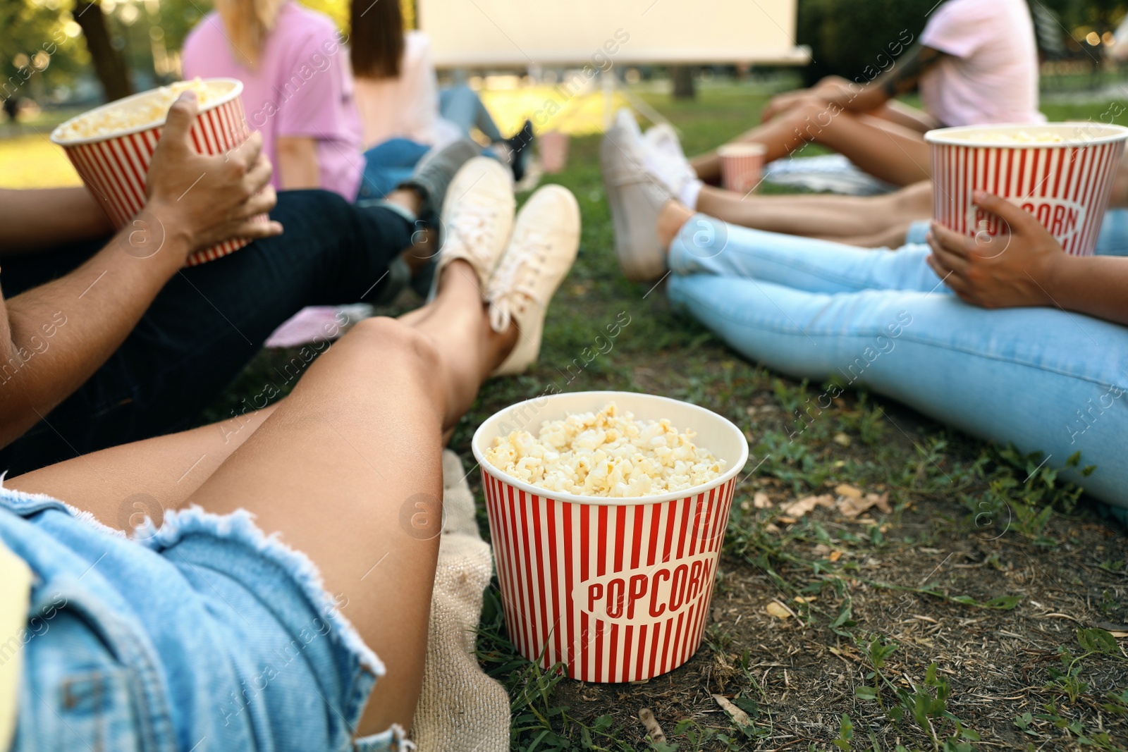 Photo of Young people with popcorn watching movie in open air cinema, closeup