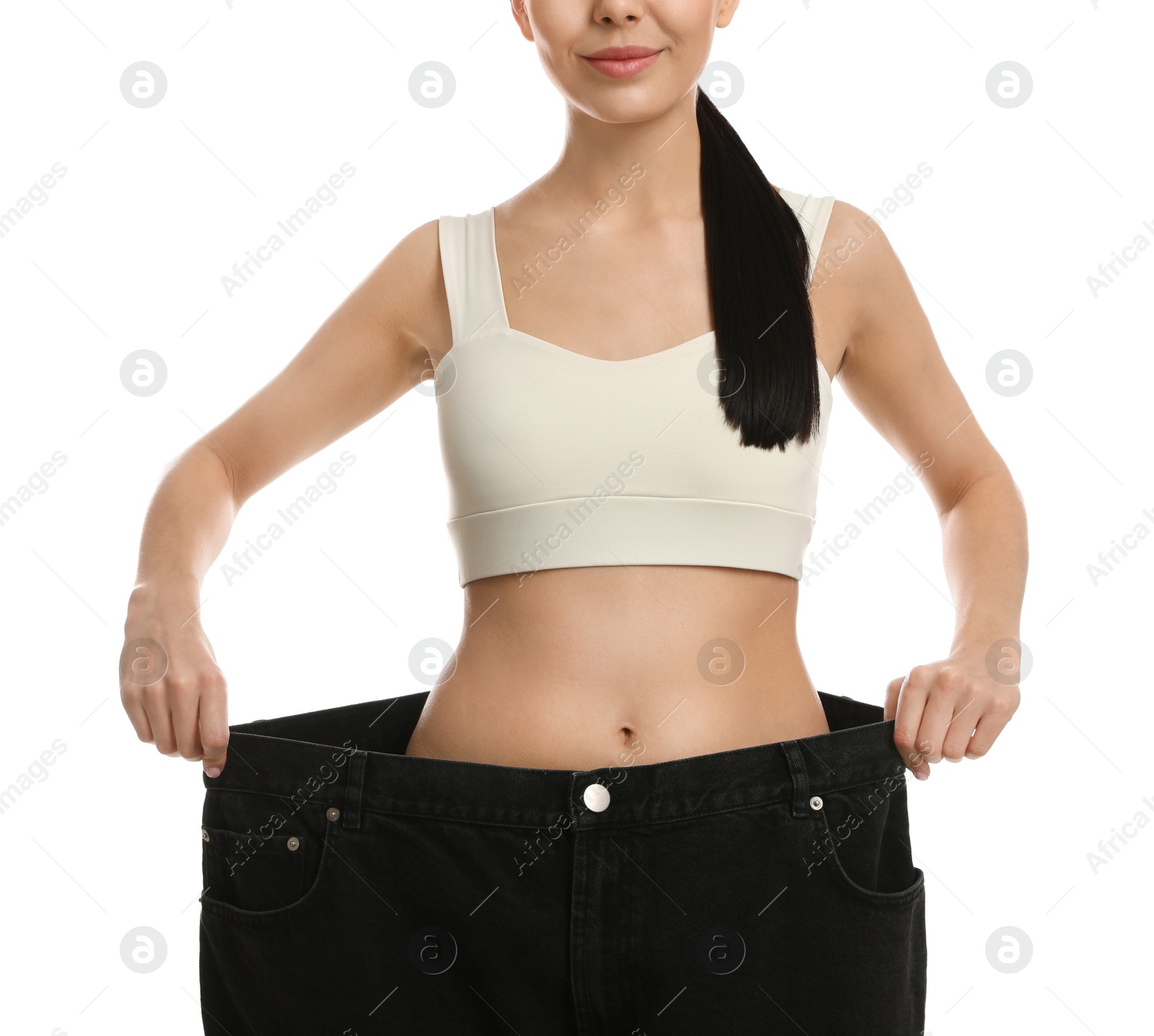 Photo of Young woman wearing big jeans after weight loss on white background, closeup