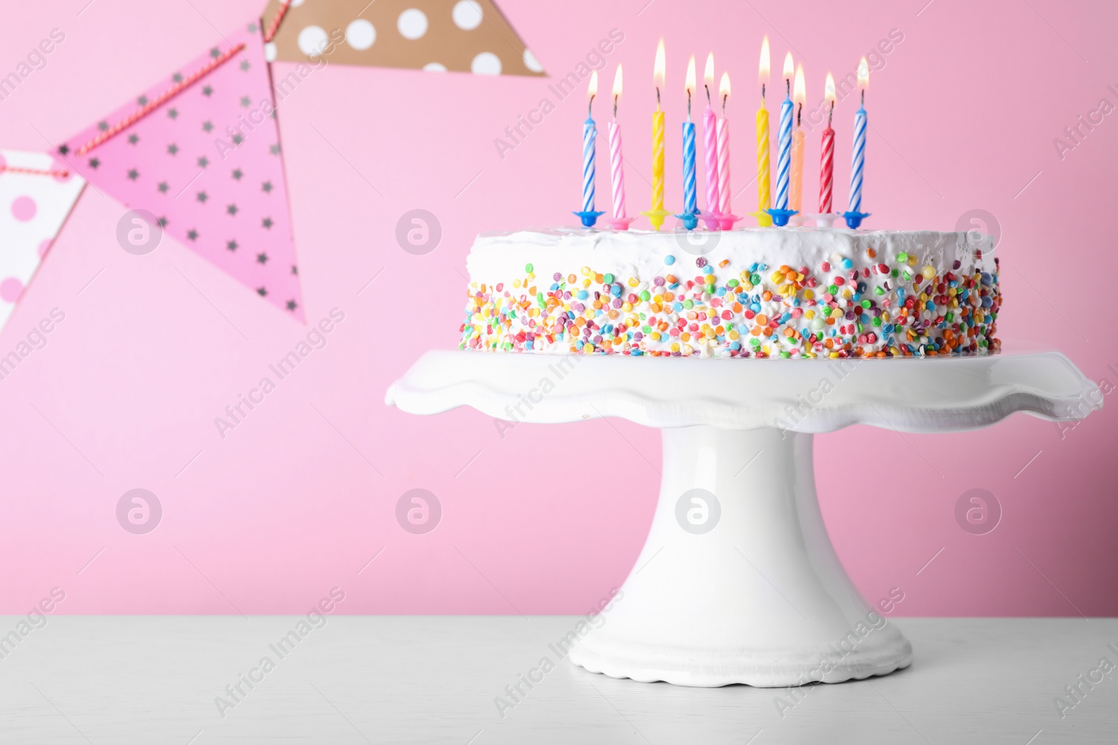 Photo of Birthday cake with burning candles on table against color background. Space for text