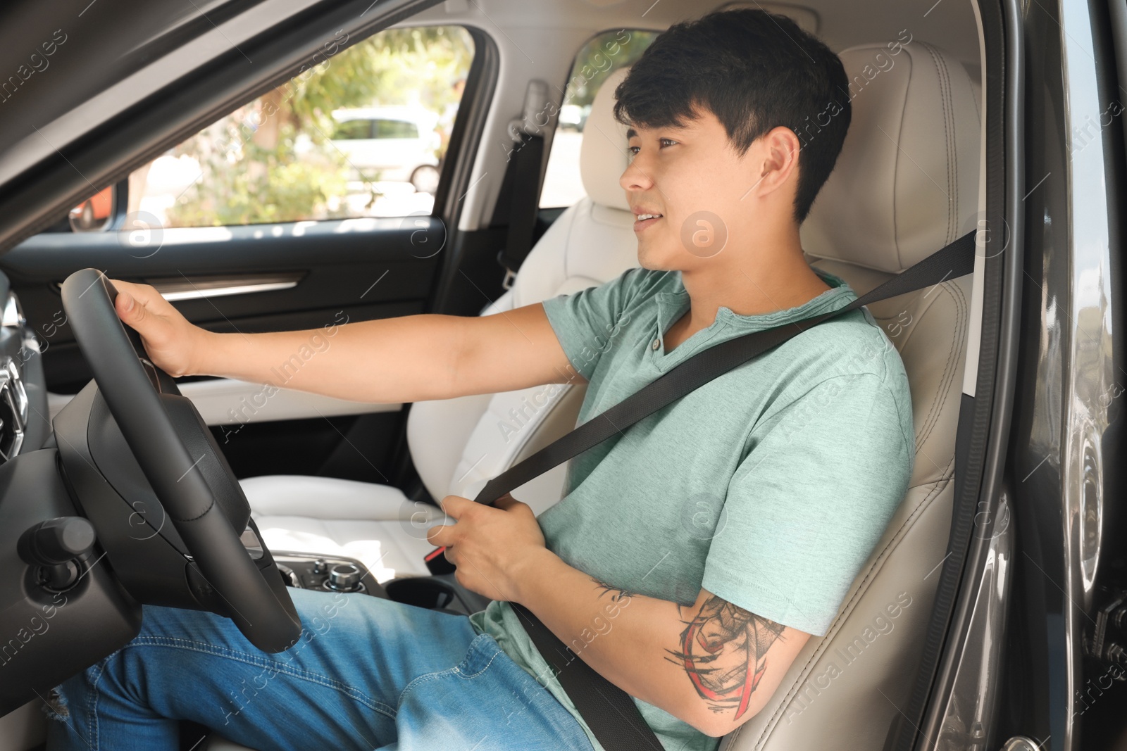 Photo of Male driver fastening safety belt in car