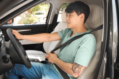 Photo of Male driver fastening safety belt in car