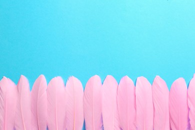 Photo of Beautiful pink feathers on light blue background, flat lay. Space for text