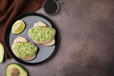 Delicious sandwiches with guacamole, avocados and black sesame seeds on brown table, flat lay. Space for text