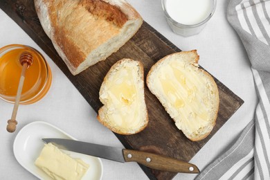 Photo of Sandwiches with butter, honey and milk on white table, flat lay