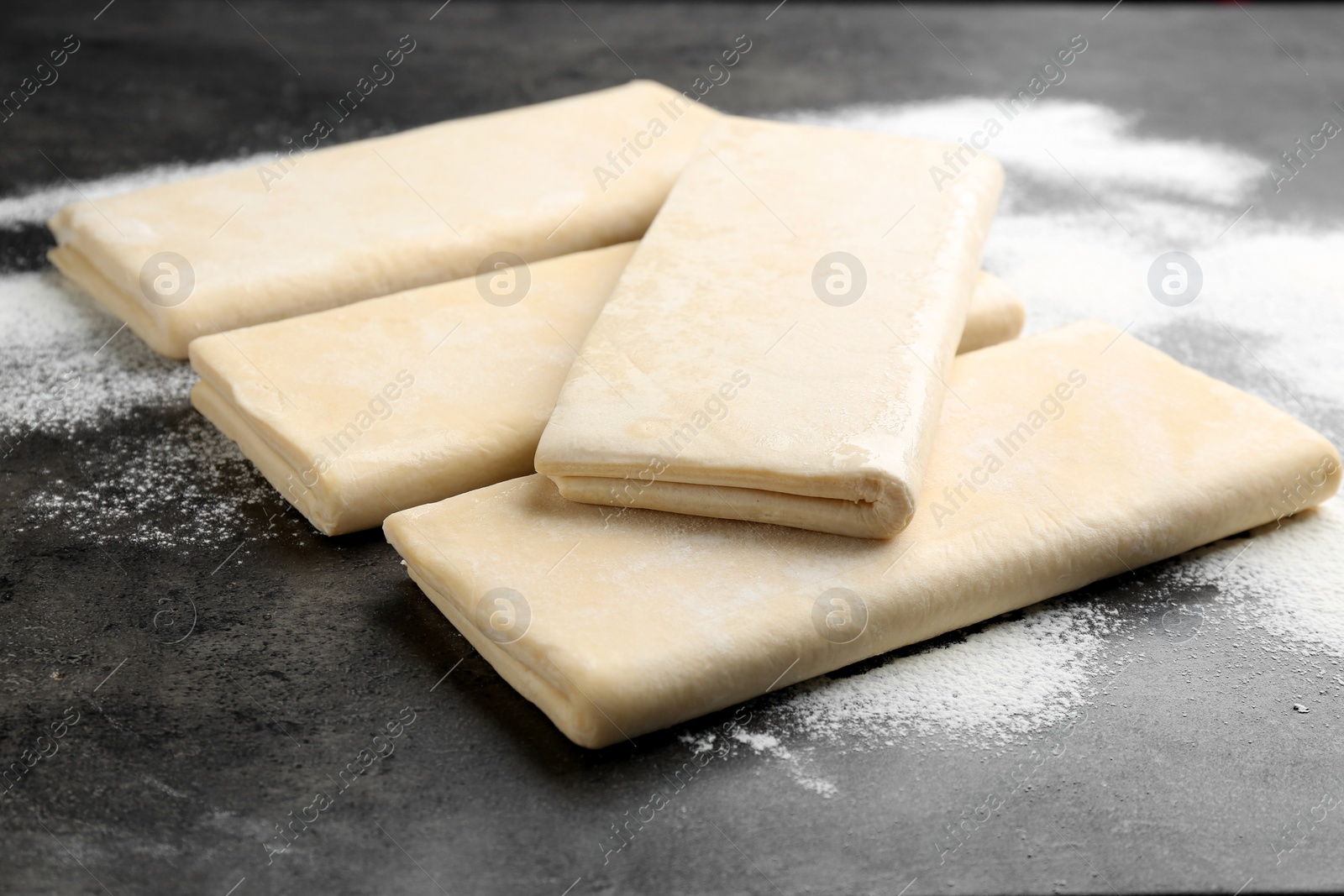 Photo of Raw wheat dough and flour on grey table