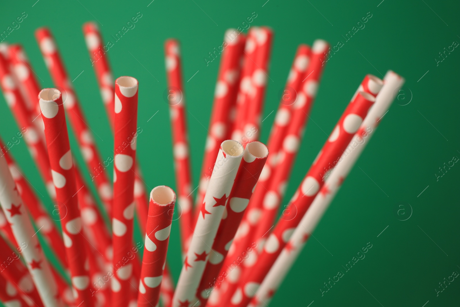 Photo of Bright paper drinking straws on green background, closeup