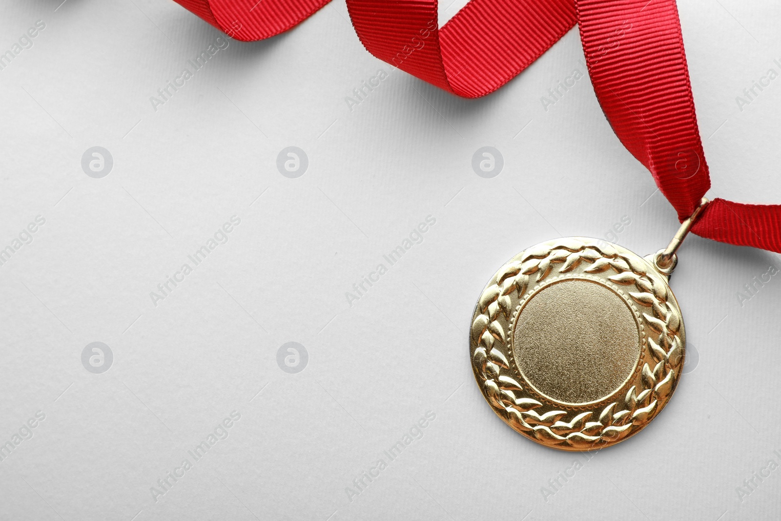 Photo of Gold medal on white background, top view with space for text. Symbol of victory