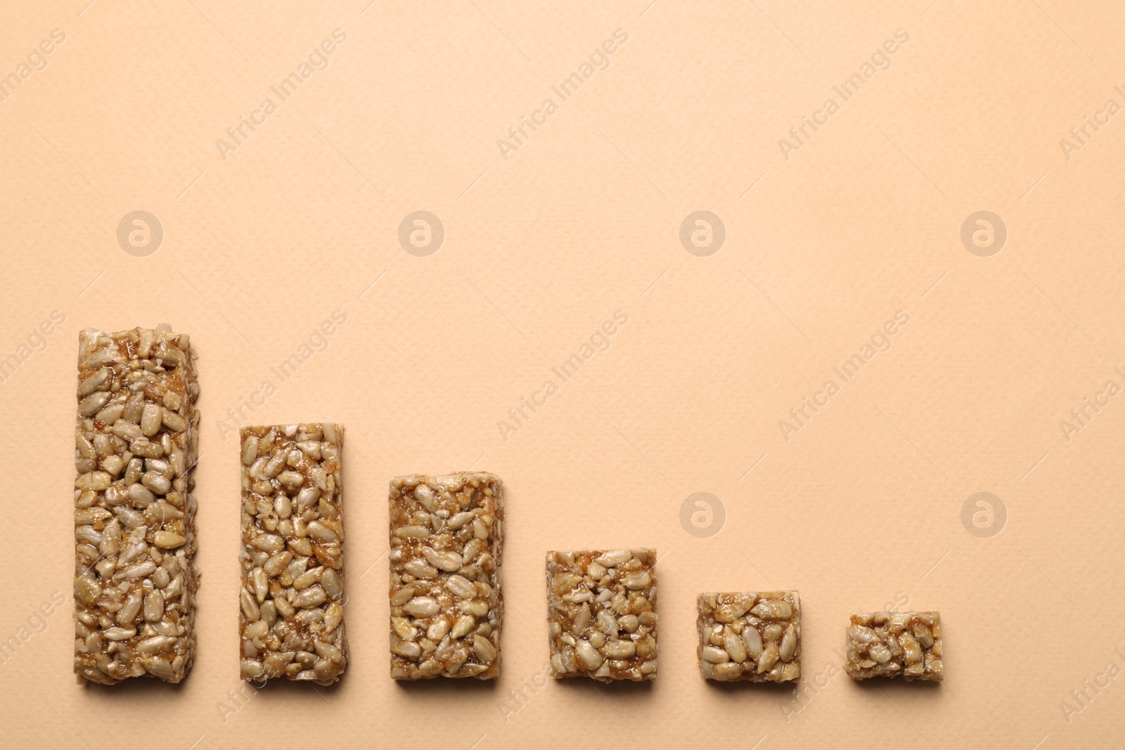 Photo of Pieces of delicious kozinaki bars on beige background, flat lay. Space for text