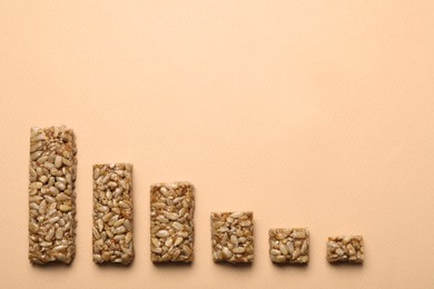 Photo of Pieces of delicious kozinaki bars on beige background, flat lay. Space for text