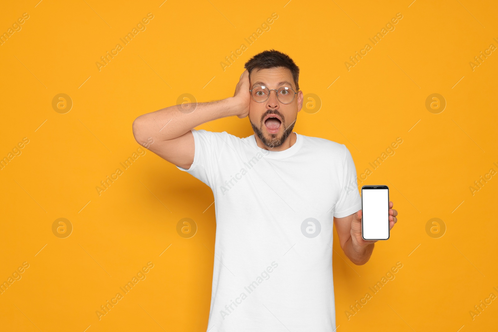 Photo of Emotional man with smartphone on orange background