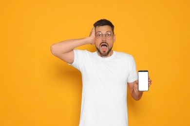 Emotional man with smartphone on orange background