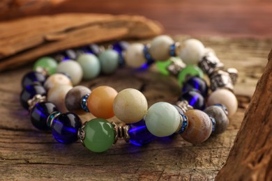 Beautiful bracelets with gemstones on wooden table, closeup