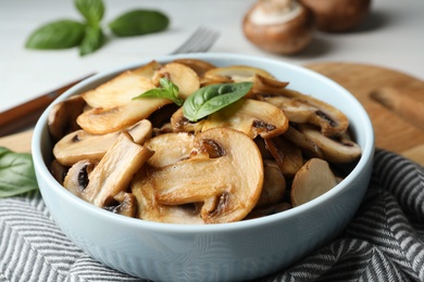 Photo of Delicious cooked mushrooms with basil served on table