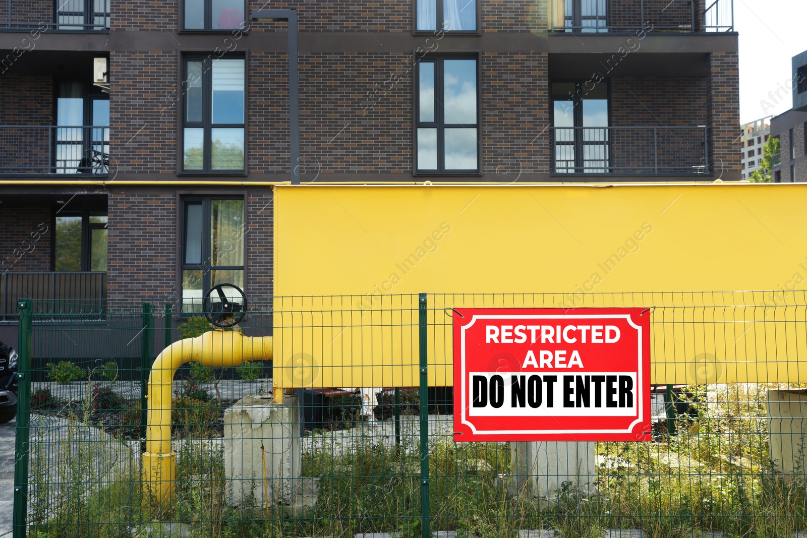 Image of Sign with text Restricted Area Do Not Enter on fence outdoors