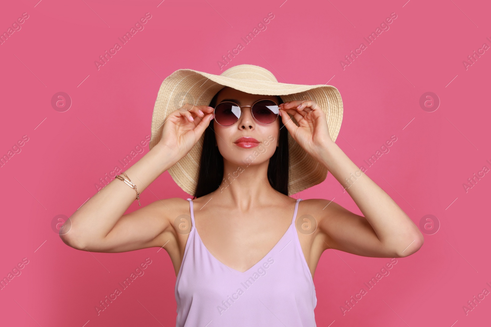 Photo of Beautiful young woman with straw hat and stylish sunglasses on pink background