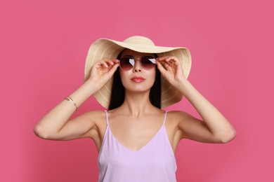 Photo of Beautiful young woman with straw hat and stylish sunglasses on pink background
