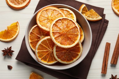 Photo of Many dry orange slices and spices on white wooden table, flat lay