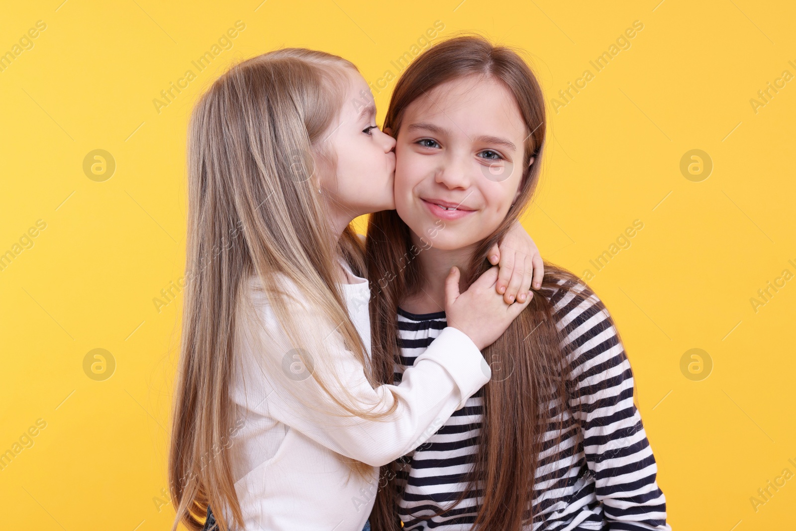 Photo of Portrait of cute little sisters on orange background