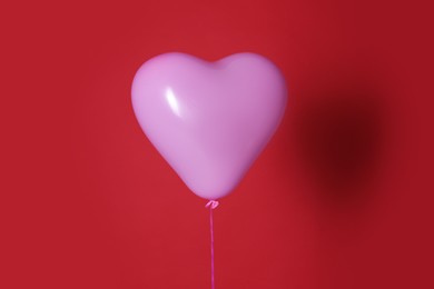 Photo of Festive heart shaped balloon on red background