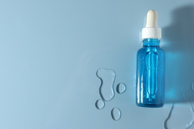 Bottle of cosmetic serum on light blue background, top view. Space for text