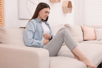 Photo of Young woman suffering from stomach pain at home