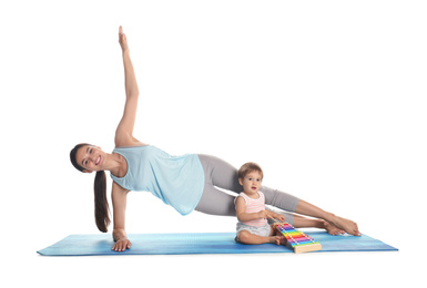 Photo of Young woman doing exercise while her son playing with toy xylophone isolated on white. Time for fitness