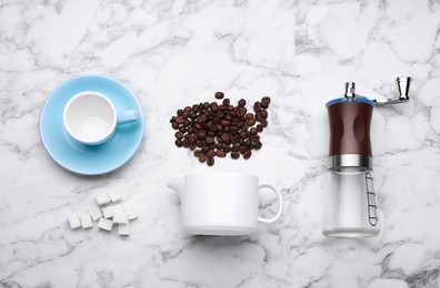Photo of Flat lay composition with manual coffee grinder and beans on white marble table
