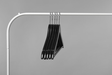 Photo of Black clothes hangers on rack against grey background