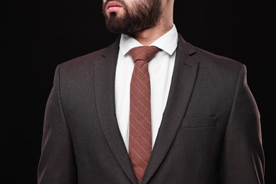 Photo of Businessman in suit and necktie on black background, closeup