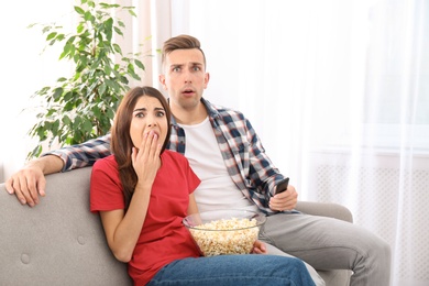 Photo of Young couple watching TV on sofa at home