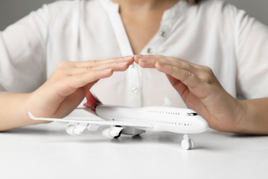 Woman covering toy plane at white table, closeup. Logistics and wholesale concept