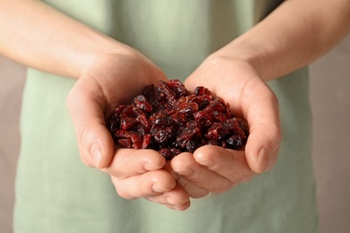 Photo of Woman holding handful of tasty cranberries on color background, closeup. Dried fruits as healthy snack