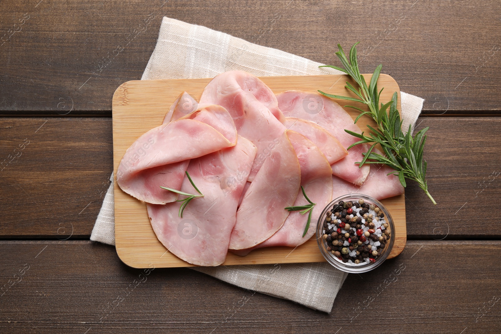 Photo of Slices of delicious ham with rosemary and spices on wooden table, top view