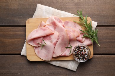 Slices of delicious ham with rosemary and spices on wooden table, top view